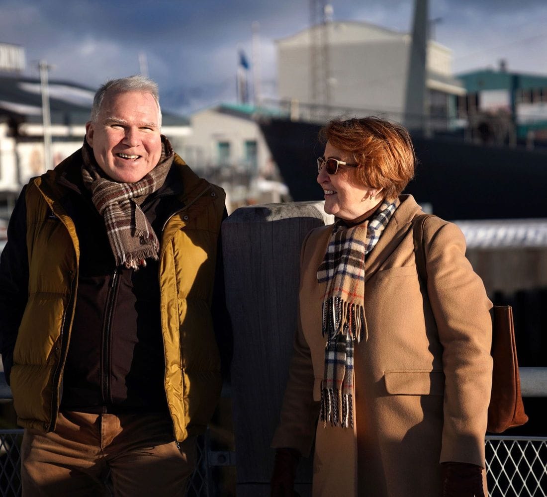 Kona og maður á bryggju að tala saman