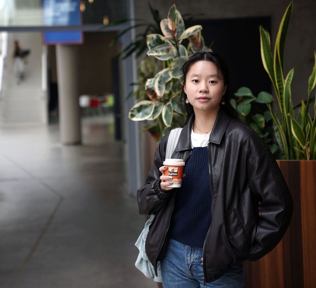 Ung kona með kaffibolla horfir í myndavél